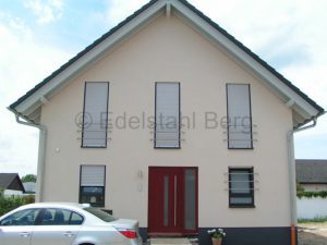 Sicherheit am Haus, Einbruchschutz, Absturzschutz: Fenstergitter aus waagrechten Edelstahl-Rundrohren, die außen zu einem Viertelkreis gebogen sind und in der Wand fest verklebt