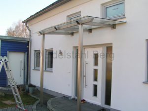 Vordach aus Edelstahl-Vierkantrohr 80 x 80 mm und Glas (VSG, Verbundsicherheitsglas). Befestigung: Stehend auf Pfosten aus Edelstahl- Vierkantrohr 80 x 80 mm. Reichelsheim, Odenwald, Hessen