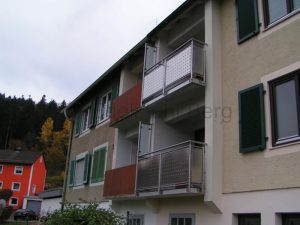 Balkongeländer aus Edelstahl mit Füllung aus Edelstahl-Lochblech, Befestigung von vorne. Seitlich wurde ein Sichtschutz zum Nachbarbalkon aus Milchglas angebracht