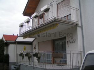Balkongeländer aus Edelstahl mit Füllung aus senkrechten Stäben aus Edelstahl und mit Blumenkästen aus Edelstahlblech, die mit Lochblechen aus Edelstahl versehen sind. Dielheim bei Wiesloch, Rhein-Neckar-Kreis